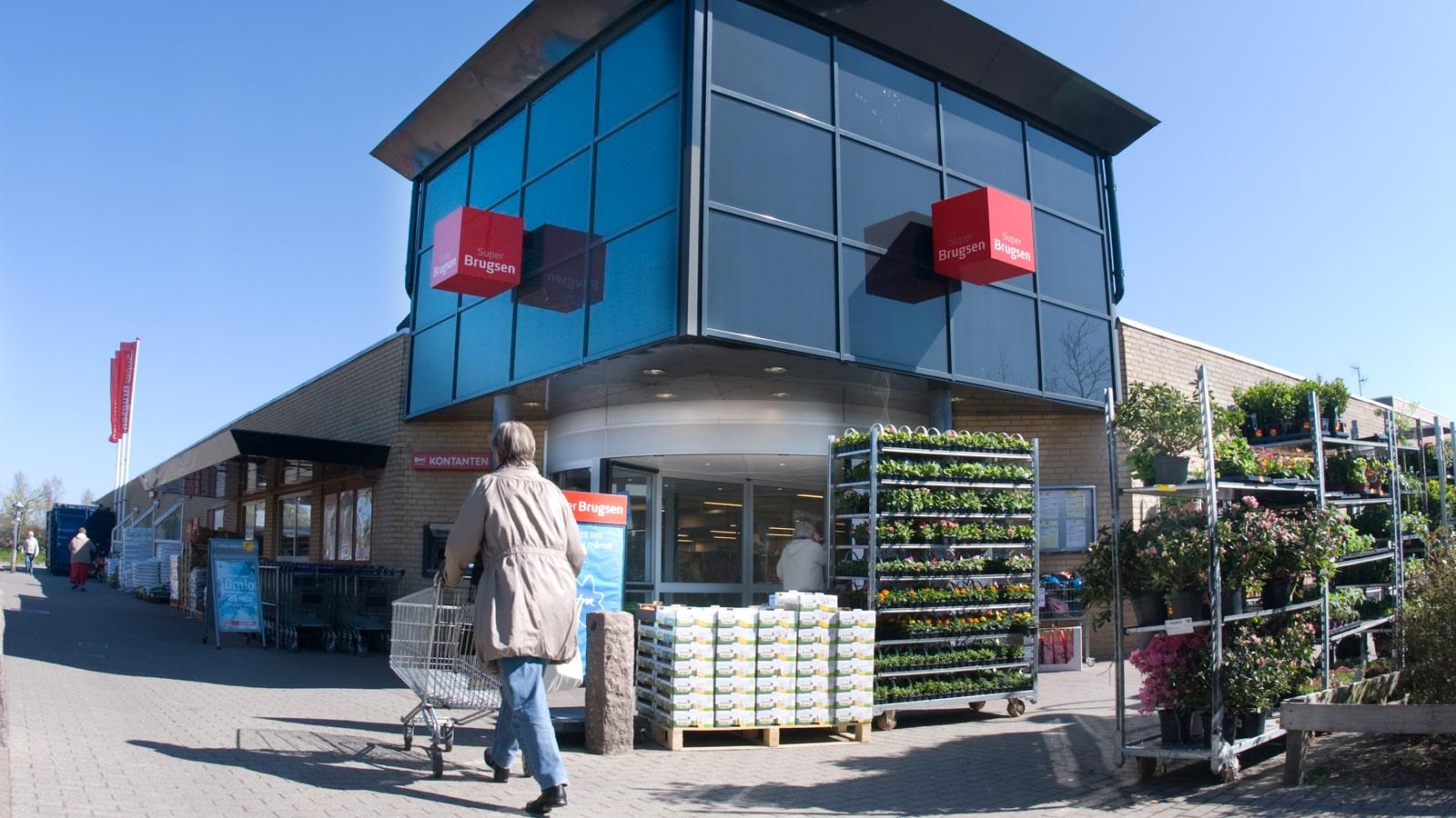 Kvinde skubber indkøbskurv mod indgangen til supermarkedet SuperBrugsen