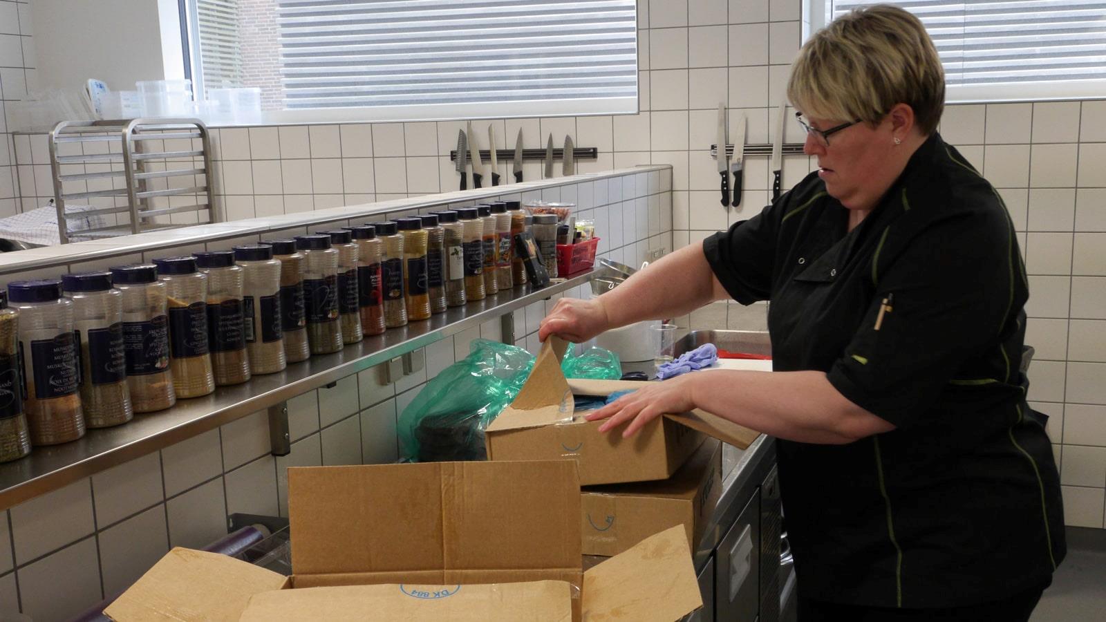 Kvindelig medarbejder åbner papkasser med dagligvarer