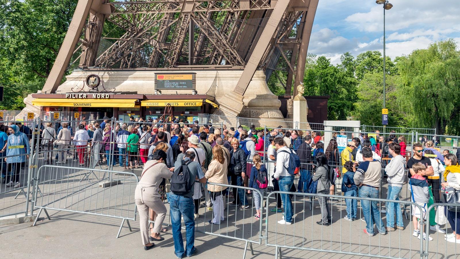 Mange turister i kø foran billetlugen til Eiffeltårnet i Paris