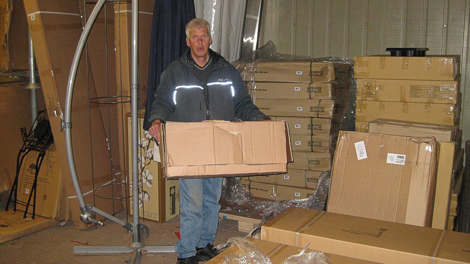 Medarbejder pakker varer ud af papkasser på lageret i havecenteret Groenrijk