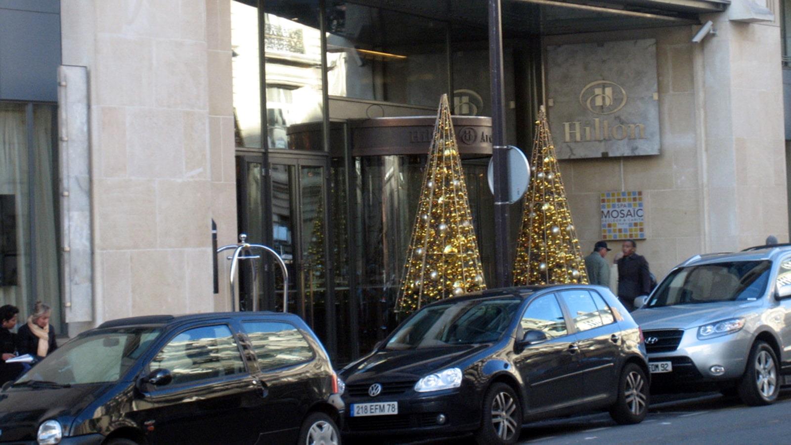 To juletræer med gylden dekoration ved indgangen til Hilton Hotel