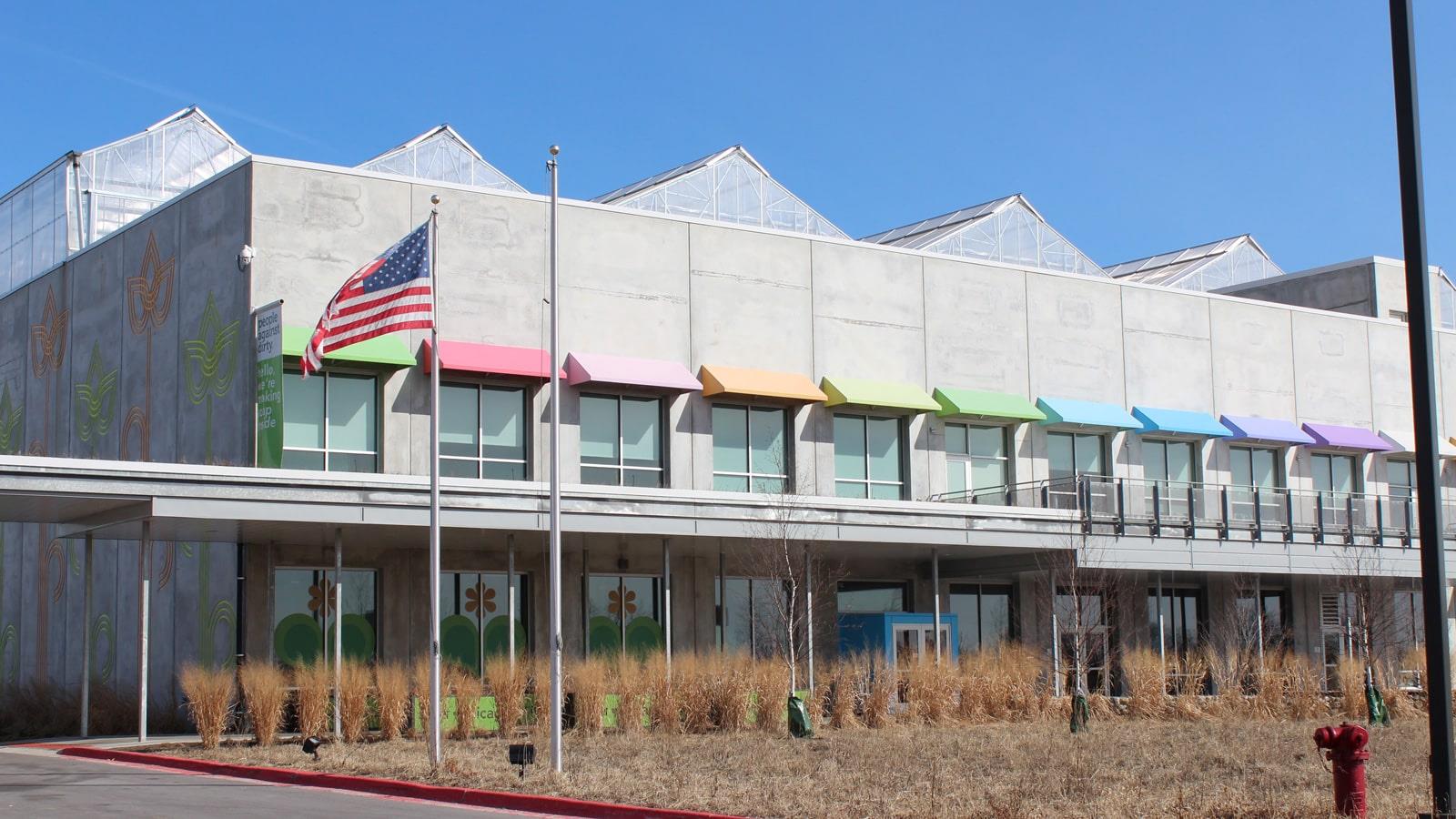 Method Homes fabrik med farverige solsejl og det amerikanske flag foran