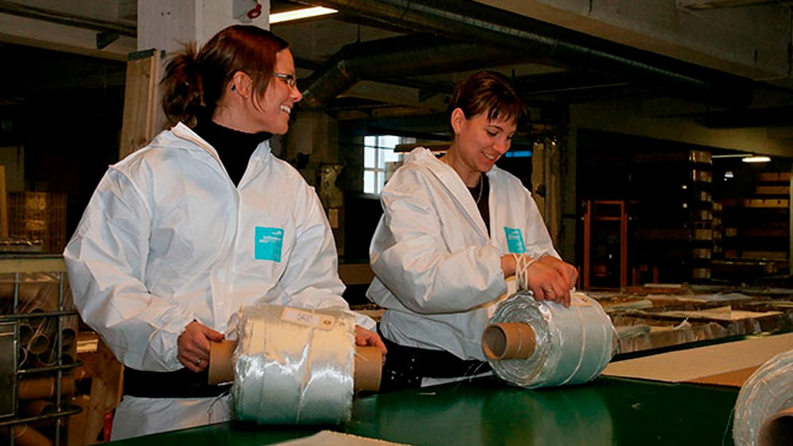 To kvindelige RewAir ansatte sætter labels på ruller med glasfiberbånd