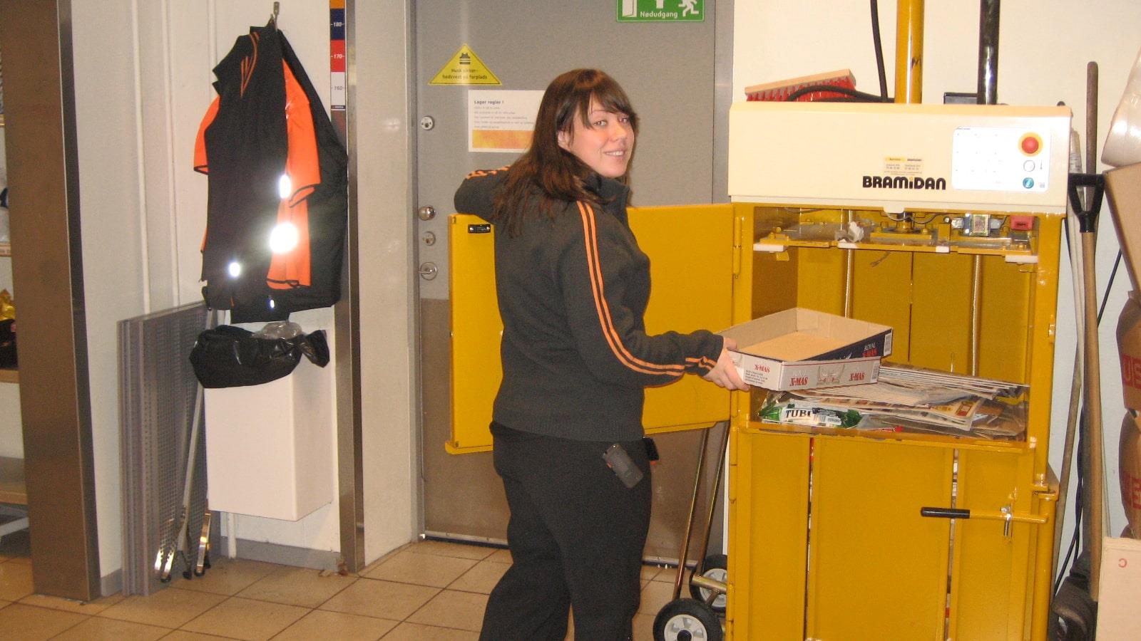 Kvinde Statoil medarbejder fylder Bramidan ballepresser med papaffald