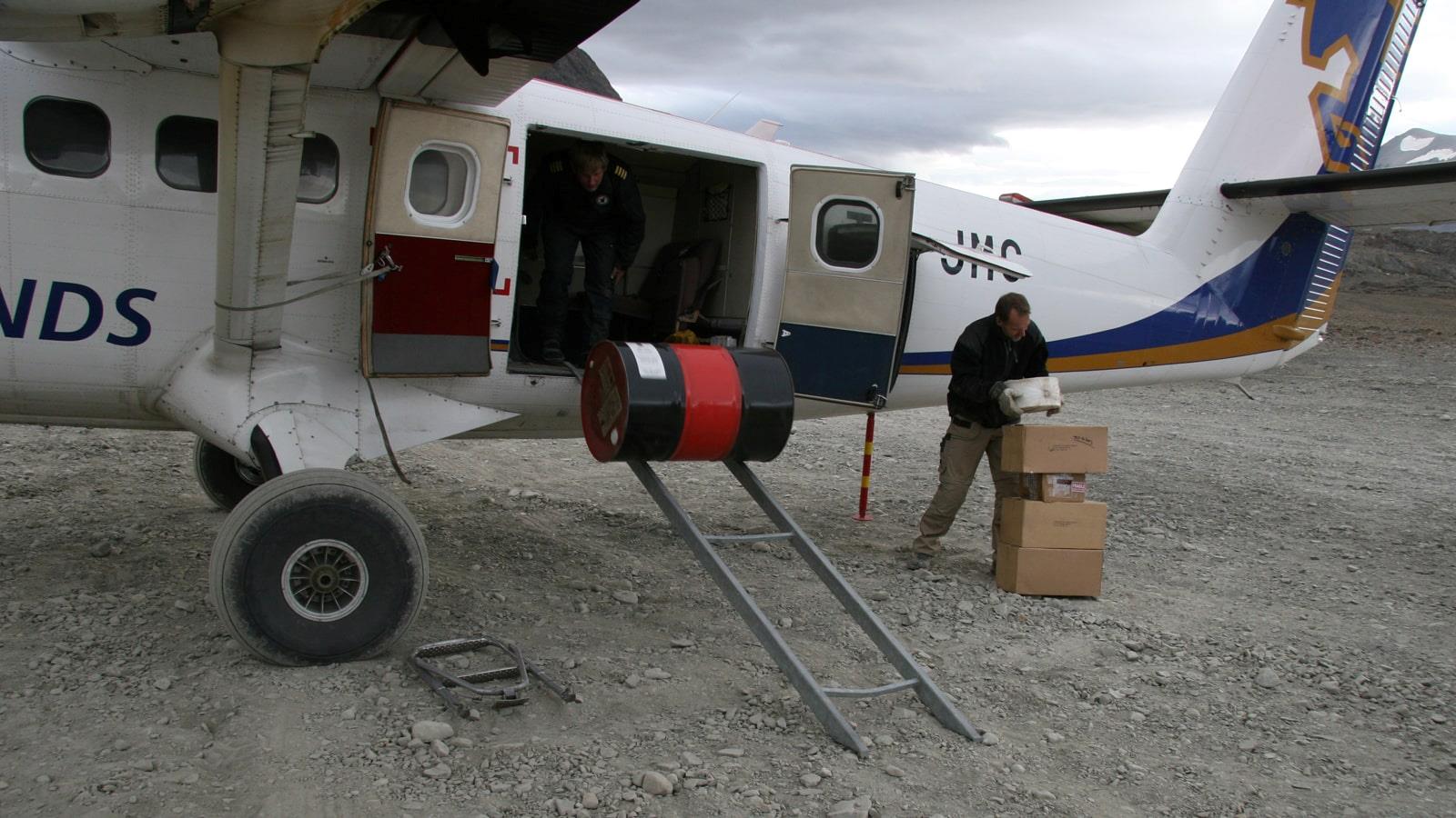 Kasser og tønder læsses af et lille fly